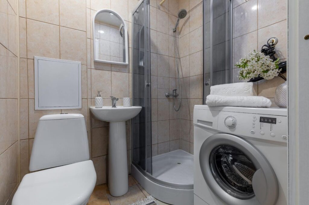 A bathroom featuring a washer and a toilet with neutral-colored walls and tiled flooring