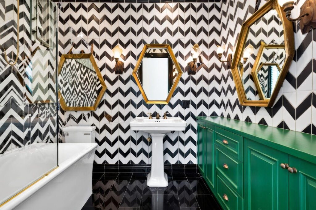 A stylish bathroom featuring black and white chevron wallpaper and elegant gold fixtures