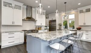 A large modern kitchen featuring white cabinets, stainless steel appliances, and a light blue central island with a granite countertop and wire bar stools.