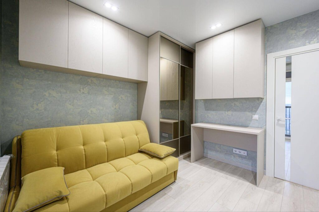 A small room featuring a yellow couch and a desk creating a cozy and inviting atmosphere