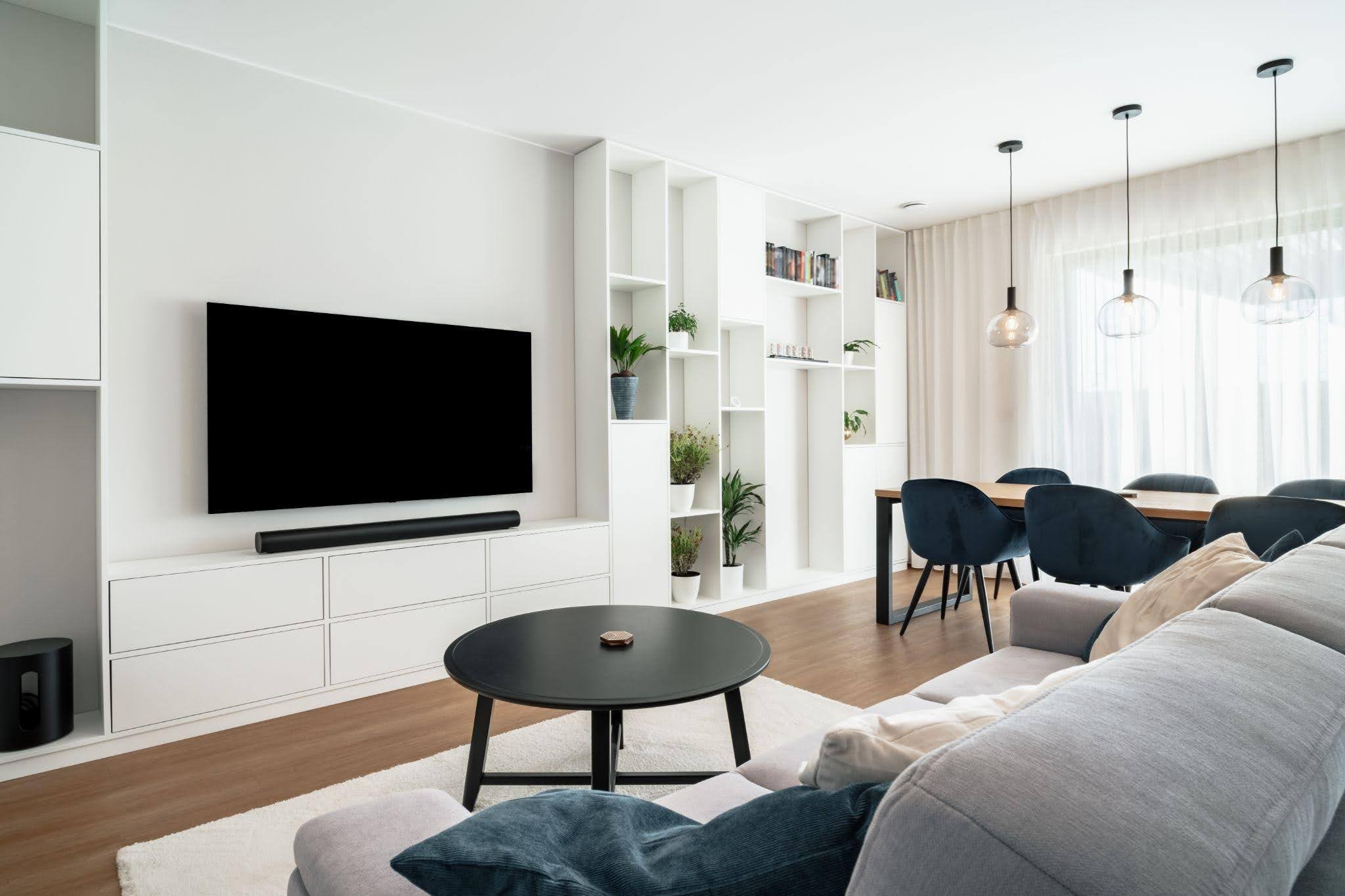 Modern living room featuring white furniture a sleek TV and a bright airy atmosphere