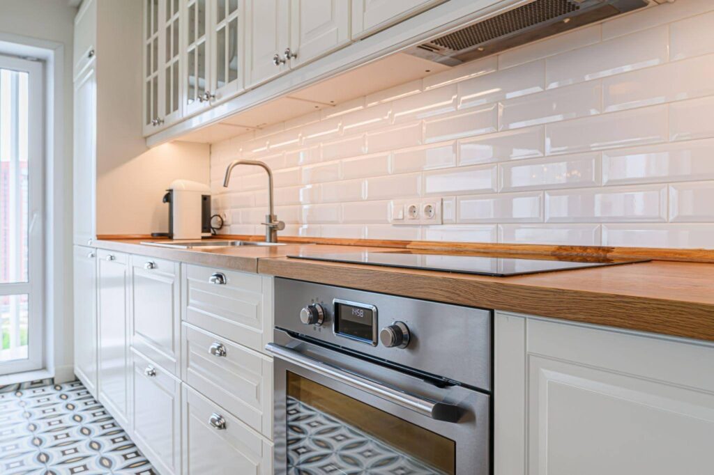 Interior view of a kitchen showcasing a sink oven and stove surrounded by cabinetry and kitchenware