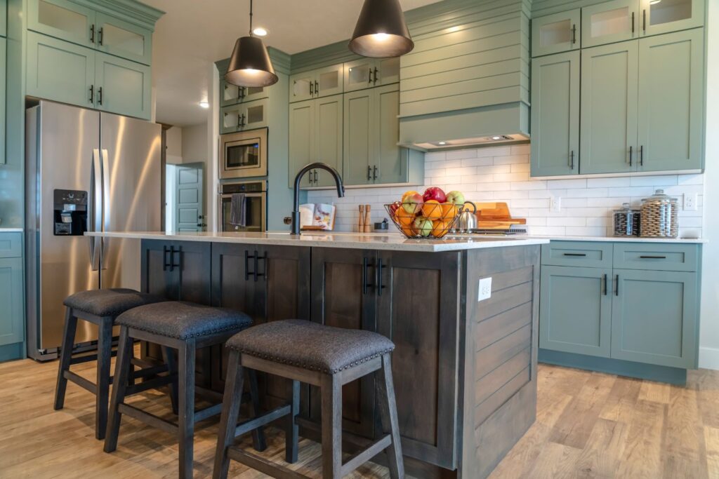 Modern kitchen with teal cabinets, a fruit bowl, and bar stools.