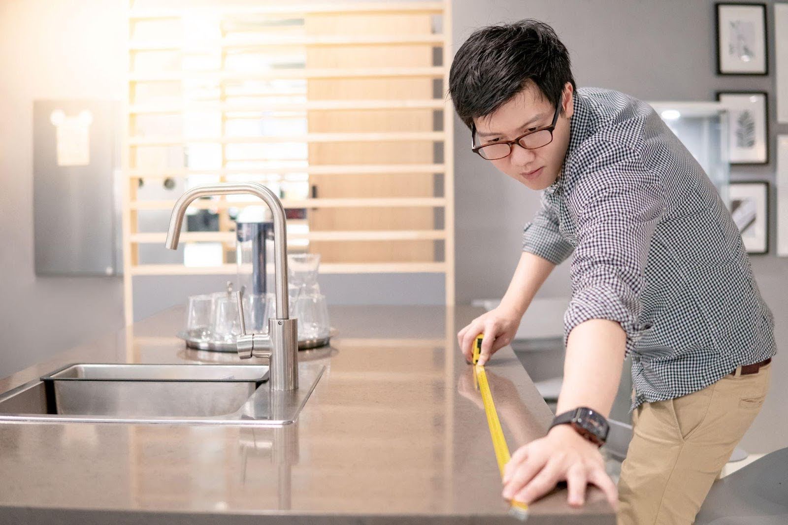 A man is carefully measuring a countertop with a ruler assessing its size for a project