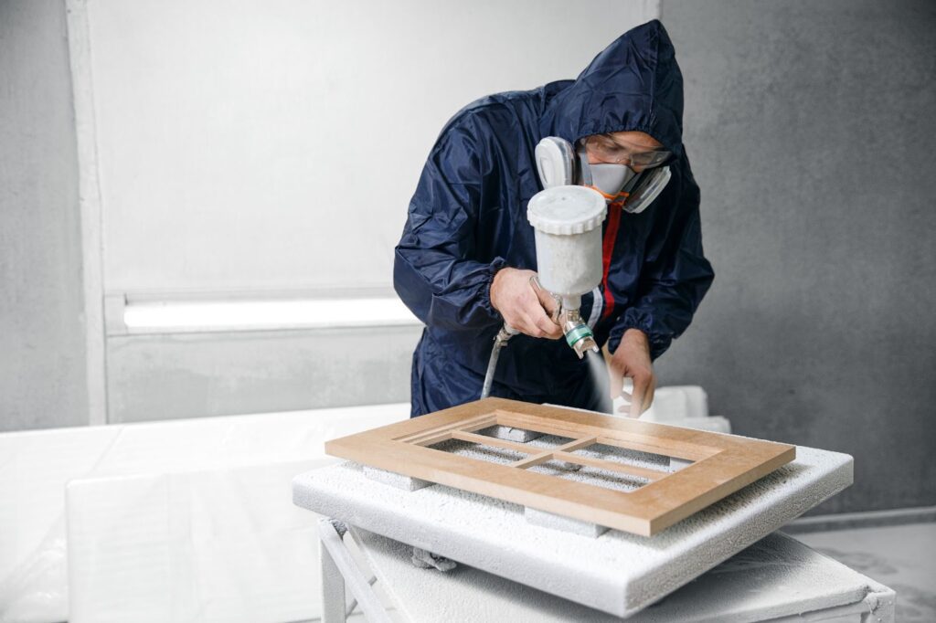 A masked man dressed in a blue suit is applying paint to a wooden door, showcasing his artistic skills.