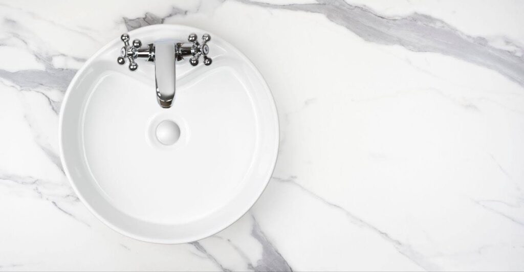 A white sink positioned on a polished marble countertop showcasing a sleek and modern design