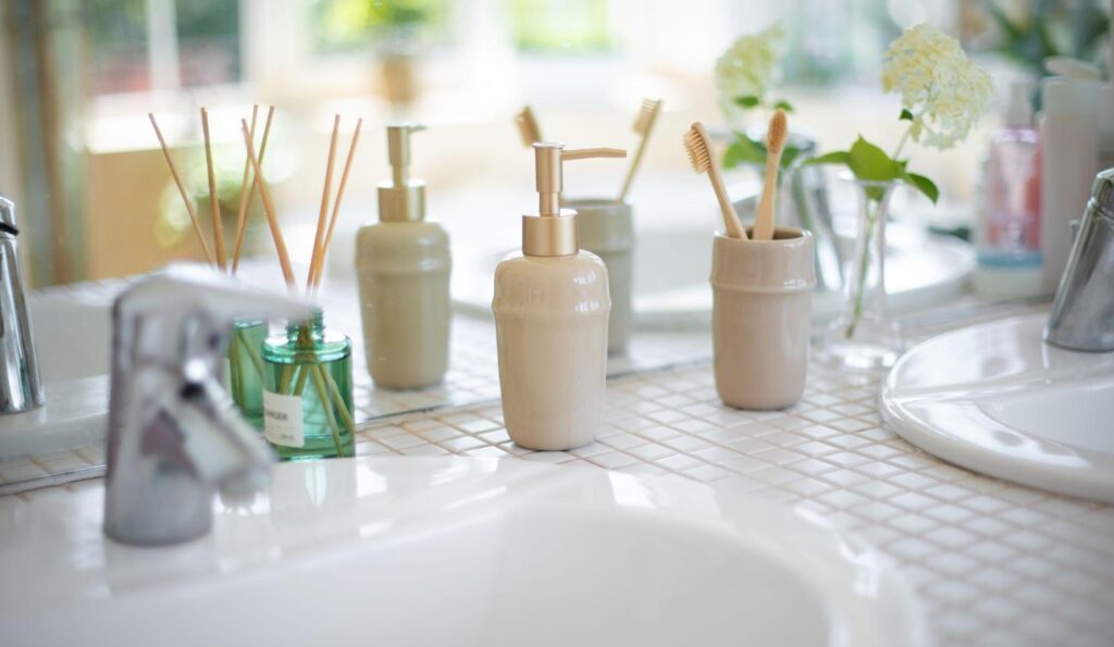 A bathroom sink displaying soap and various toiletries arranged neatly on its surface
