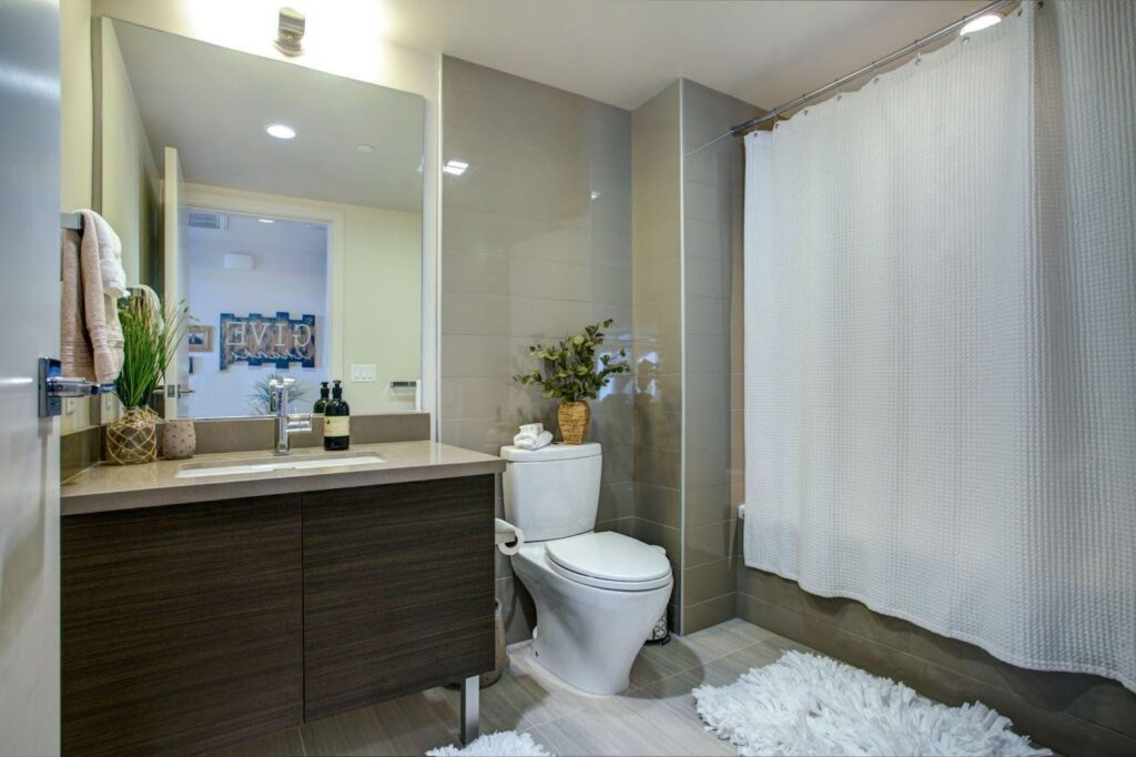 A bathroom featuring a toilet, sink and a shower curtain showcasing a clean and functional design