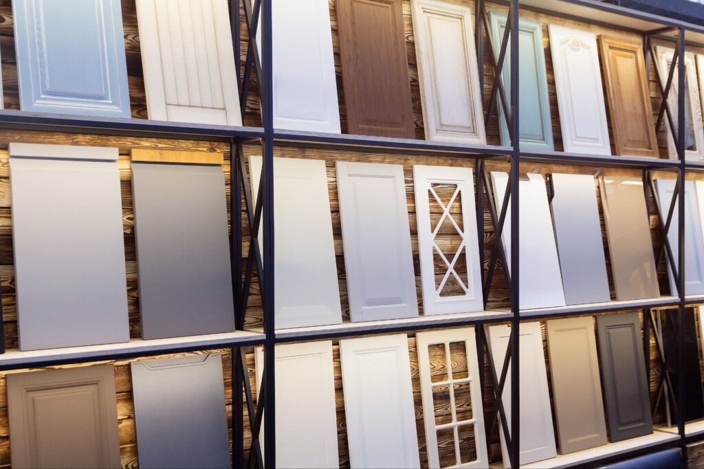 A display of various cabinet door samples in different colors, styles, and finishes arranged on shelves.