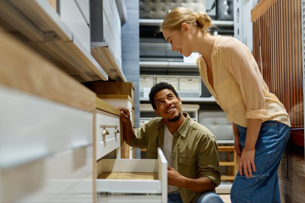 A man and woman examine a wooden cabinet discussing its features and design