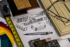 3D kitchen design blueprint surrounded by cabinet door samples, color swatches, countertops, and measuring tape