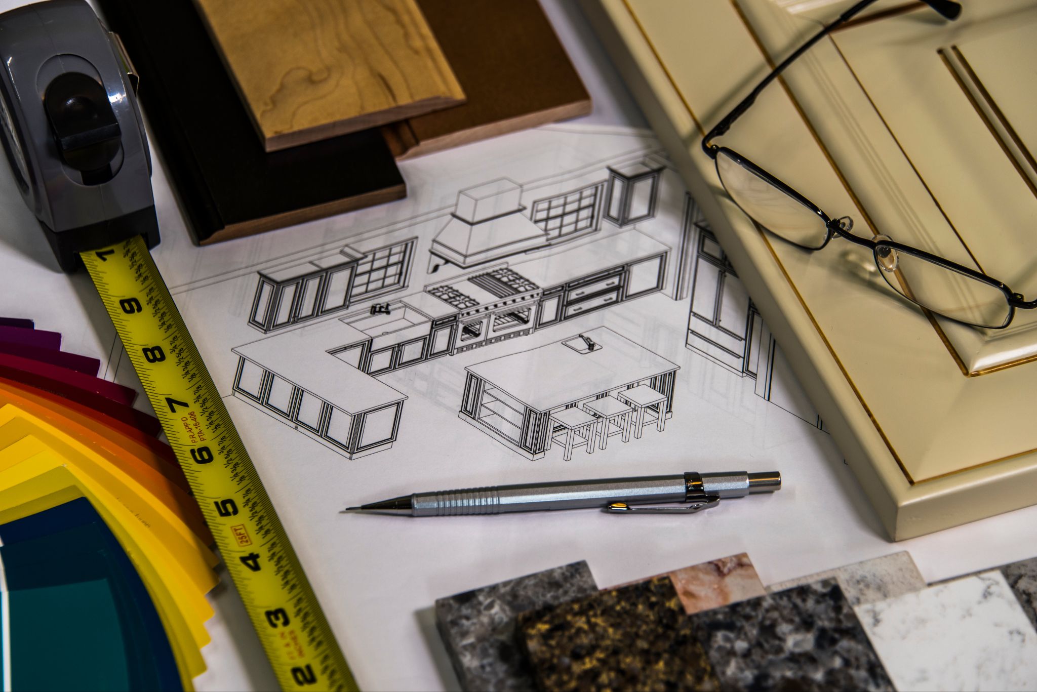 3D kitchen design blueprint surrounded by cabinet door samples, color swatches, countertops, and measuring tape