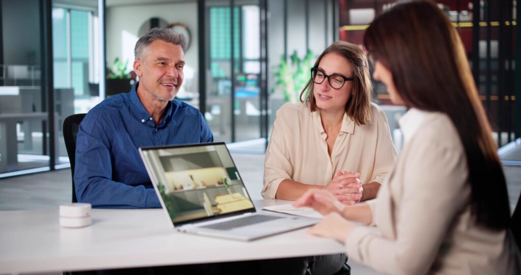 Couple meeting with a professional at a desk with a laptop open