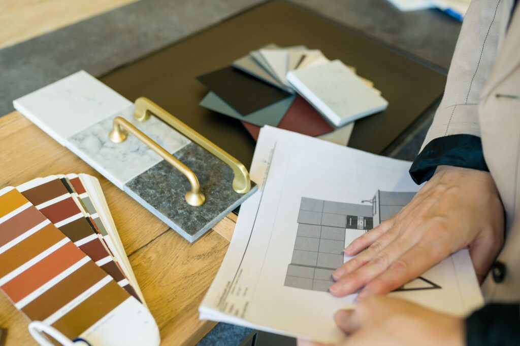 Interior designer reviewing architectural blueprints alongside color swatches, tile samples, and brass hardware