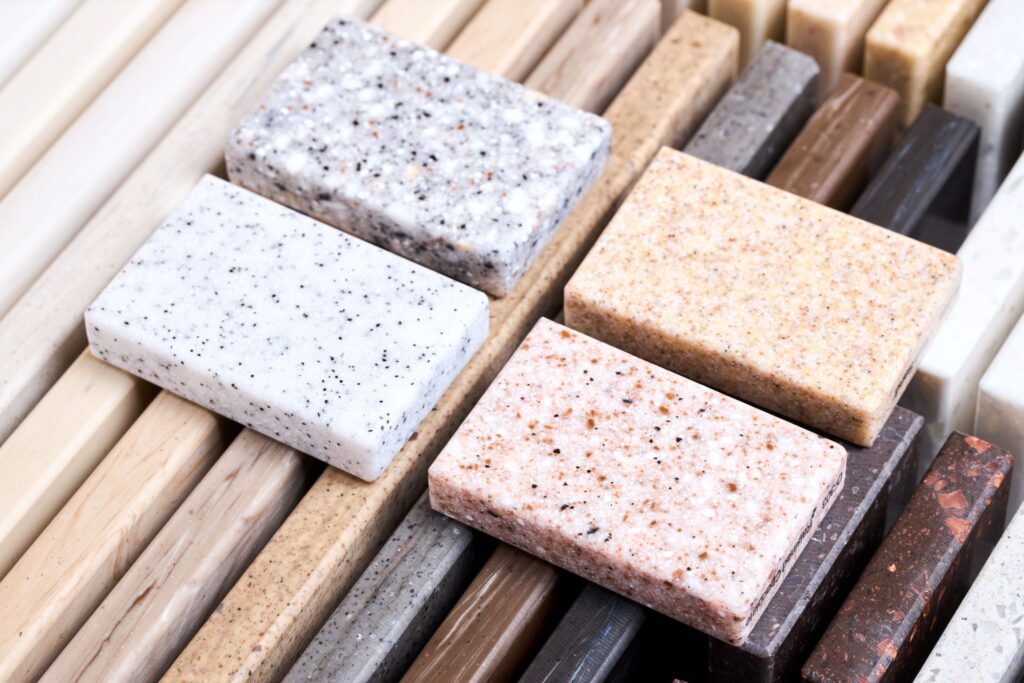 Collection of solid surface and quartz countertop material samples in various colors and finishes.