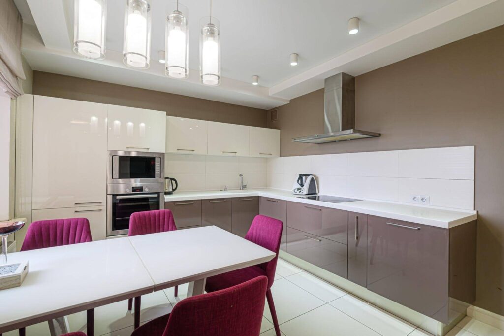 A modern kitchen featuring a dining table with chairs sleek cabinetry and contemporary appliances